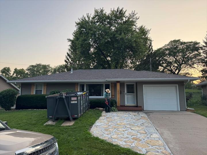 Completed roof on a ranch home at dusk with the yard cleaned up