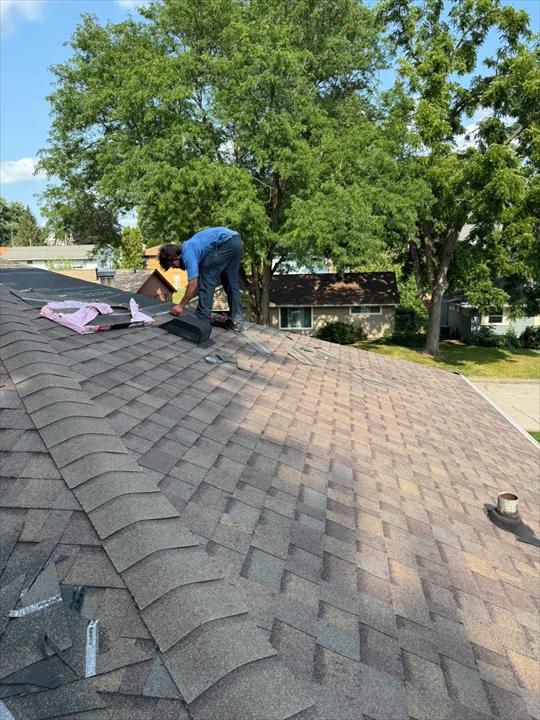 Roofer setting a ridge vent along the peak of a newly shingled roof